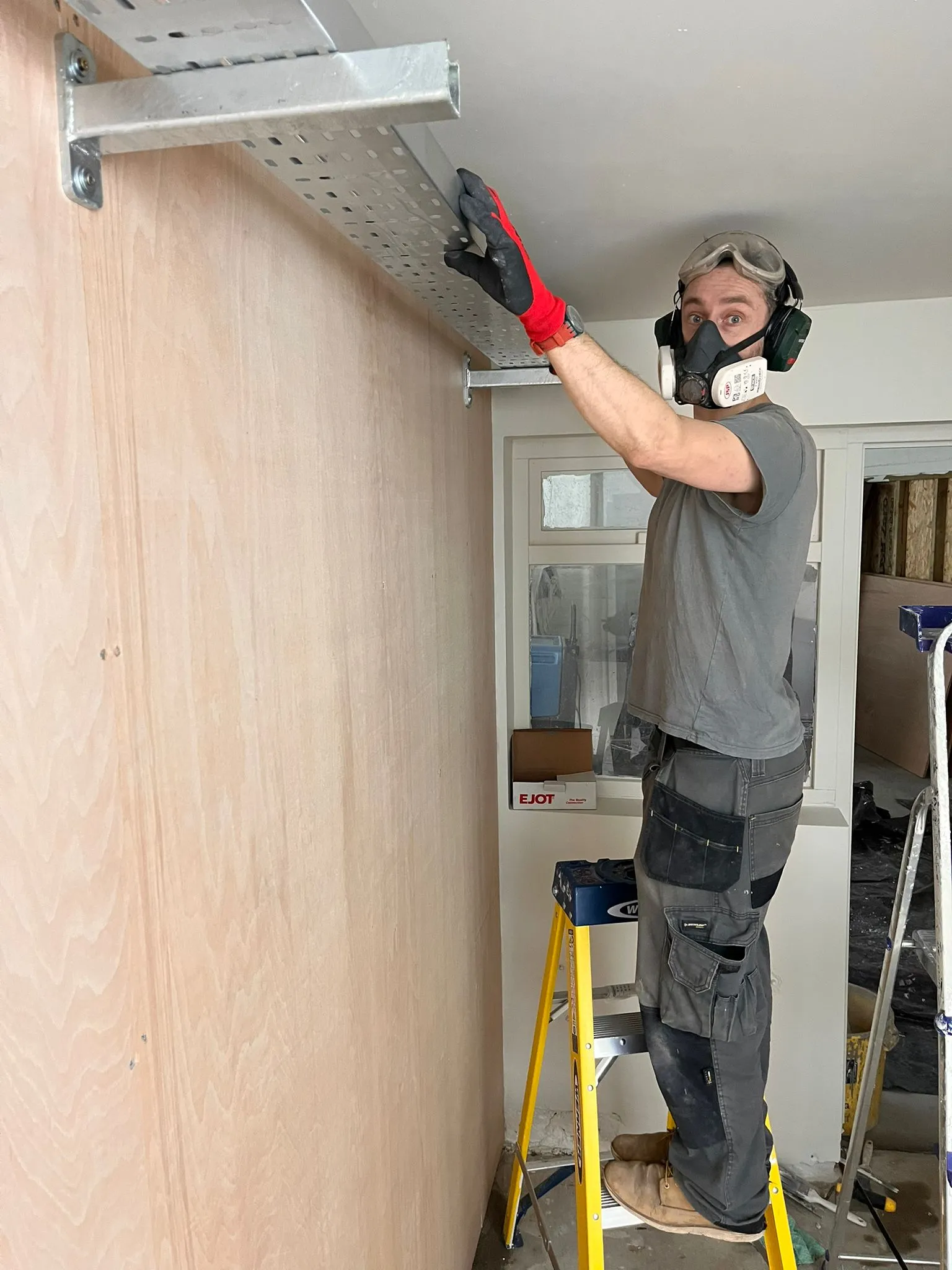 Electrician installing cable tray for commercial electrical work in North London